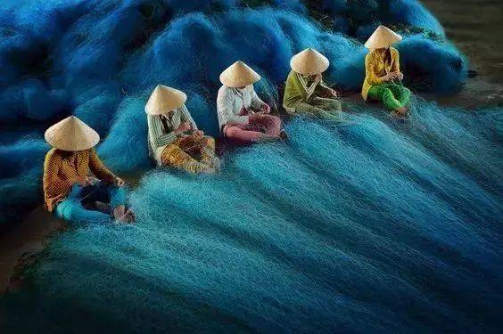 中年女人們正排排坐著，安靜地整理捕魚的紗網